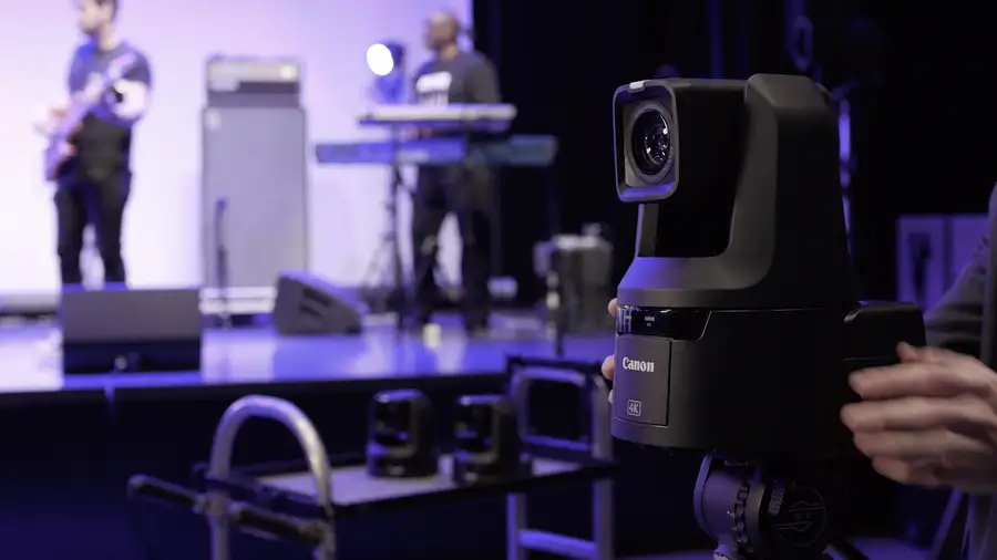 Remote-operated PTZ cameras positioned to cover a band performing on a lit stage.
