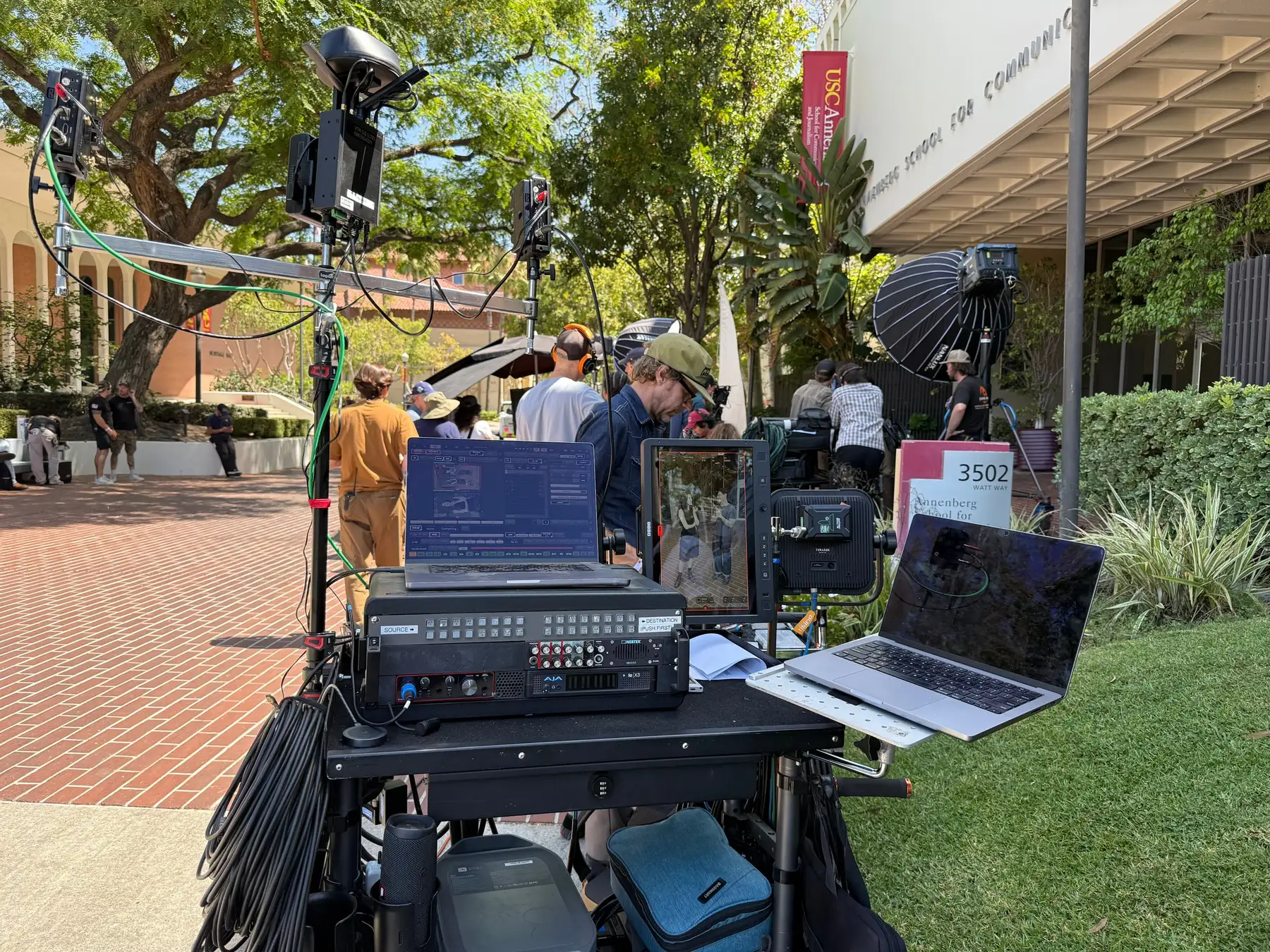 A full video-assist cart on a daytime exterior location: router, recorder, wireless transmitters, and monitors mounted on a rolling stand.